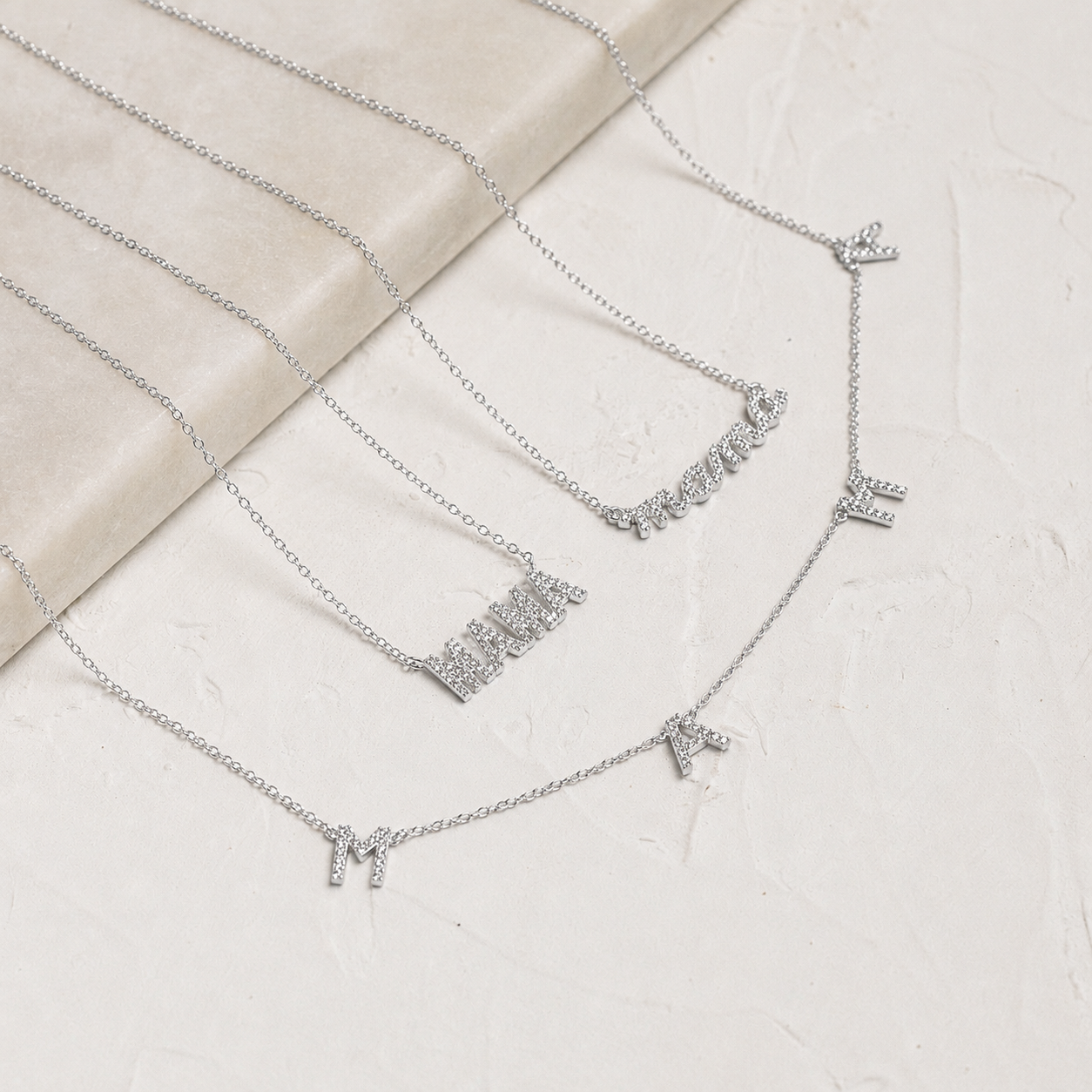 Silver necklace with letter pendants on a textured surface